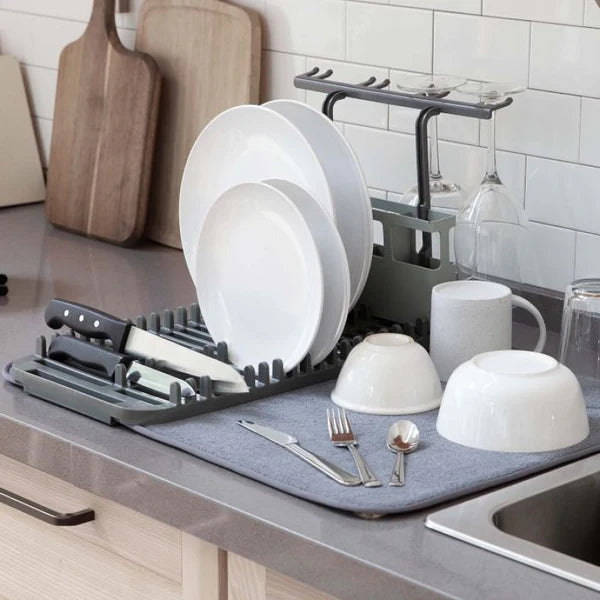 Dish rack with white dishes, cups, and cutlery on a kitchen counter.
